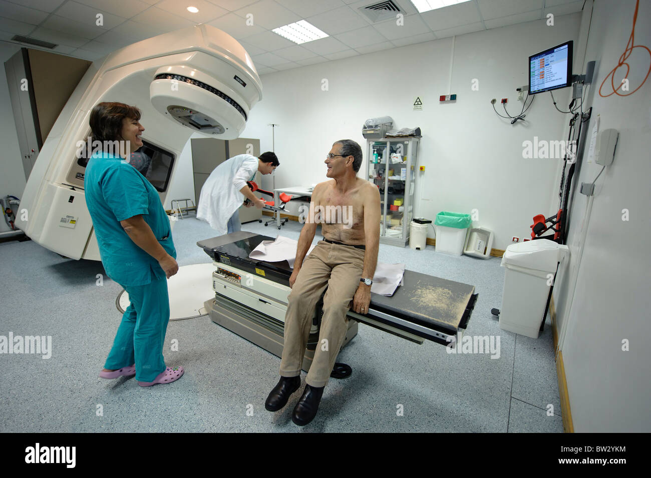 Patienten mit Arzt und Krankenschwester nach einer Strahlentherapie Behandlung mit Hilfe einer linearen Elektron Beschleuniger CLINAC 2100C/D Maschine Stockfoto