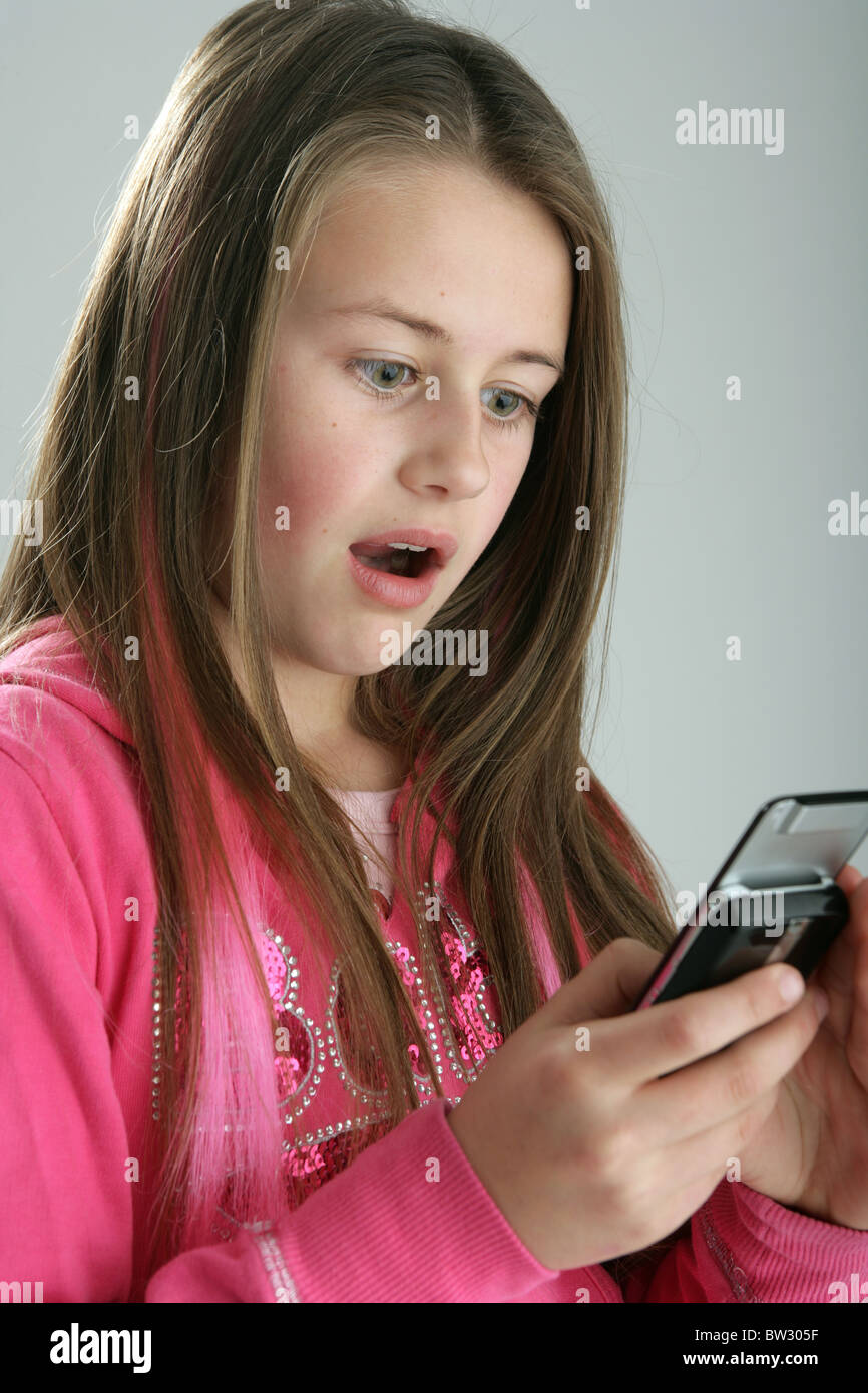 10 Jahre altes Mädchen schauen schockiert über ein Mobiltelefon. Stockfoto