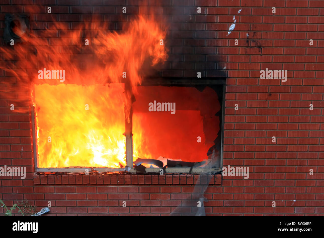 Haus in Brand nach Sonnenuntergang. Keller Mauer und Terrasse in vollen Flammen und Rauch. Totalen Verlust und Zerstörung. Fenster-Flammen. Stockfoto