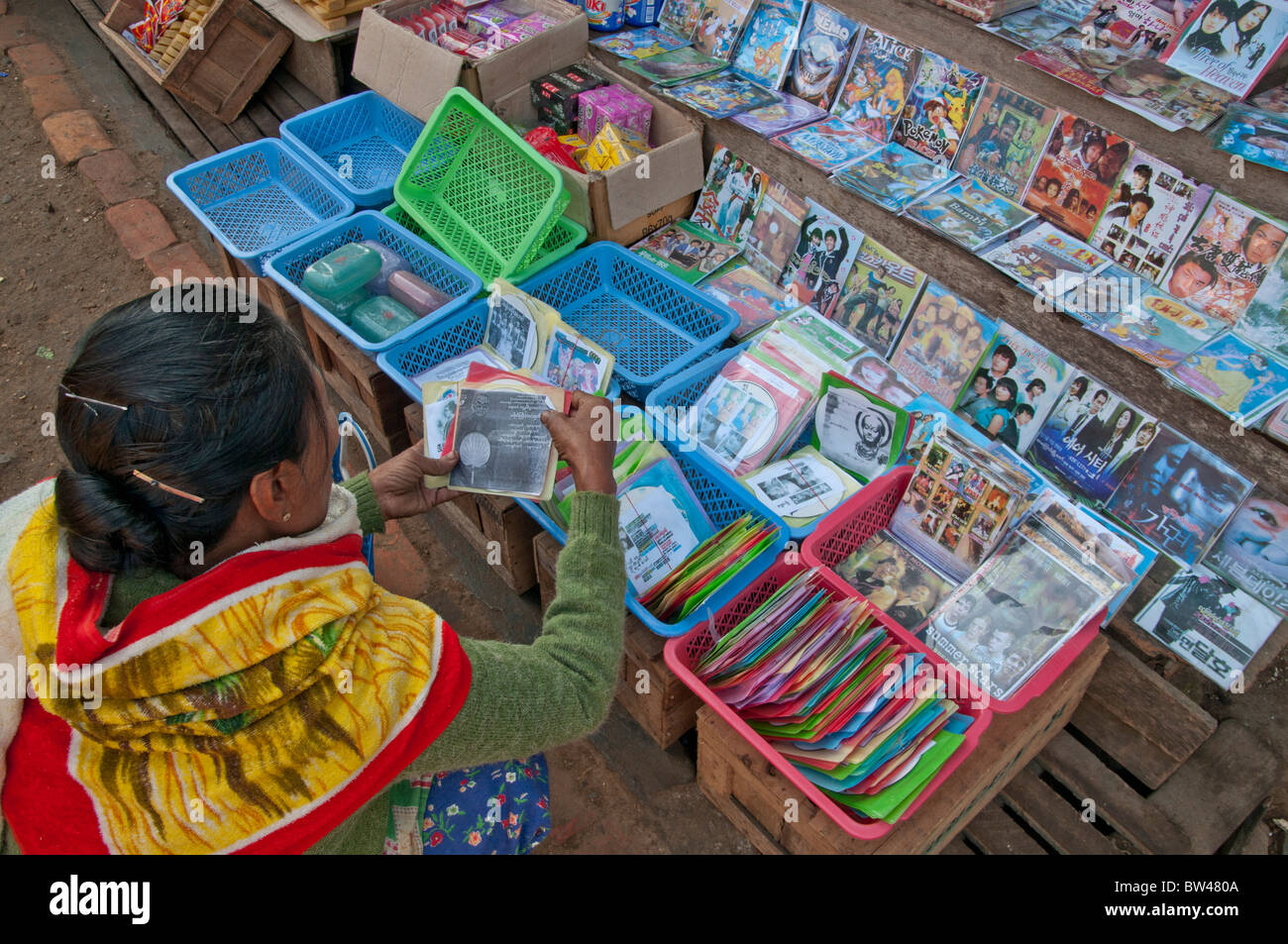 BURMA MYANMAR FRAU WÄHLEN DVD-FILME AUF EINEM MARKT IN DER NÄHE VON MANDALAY Stockfoto