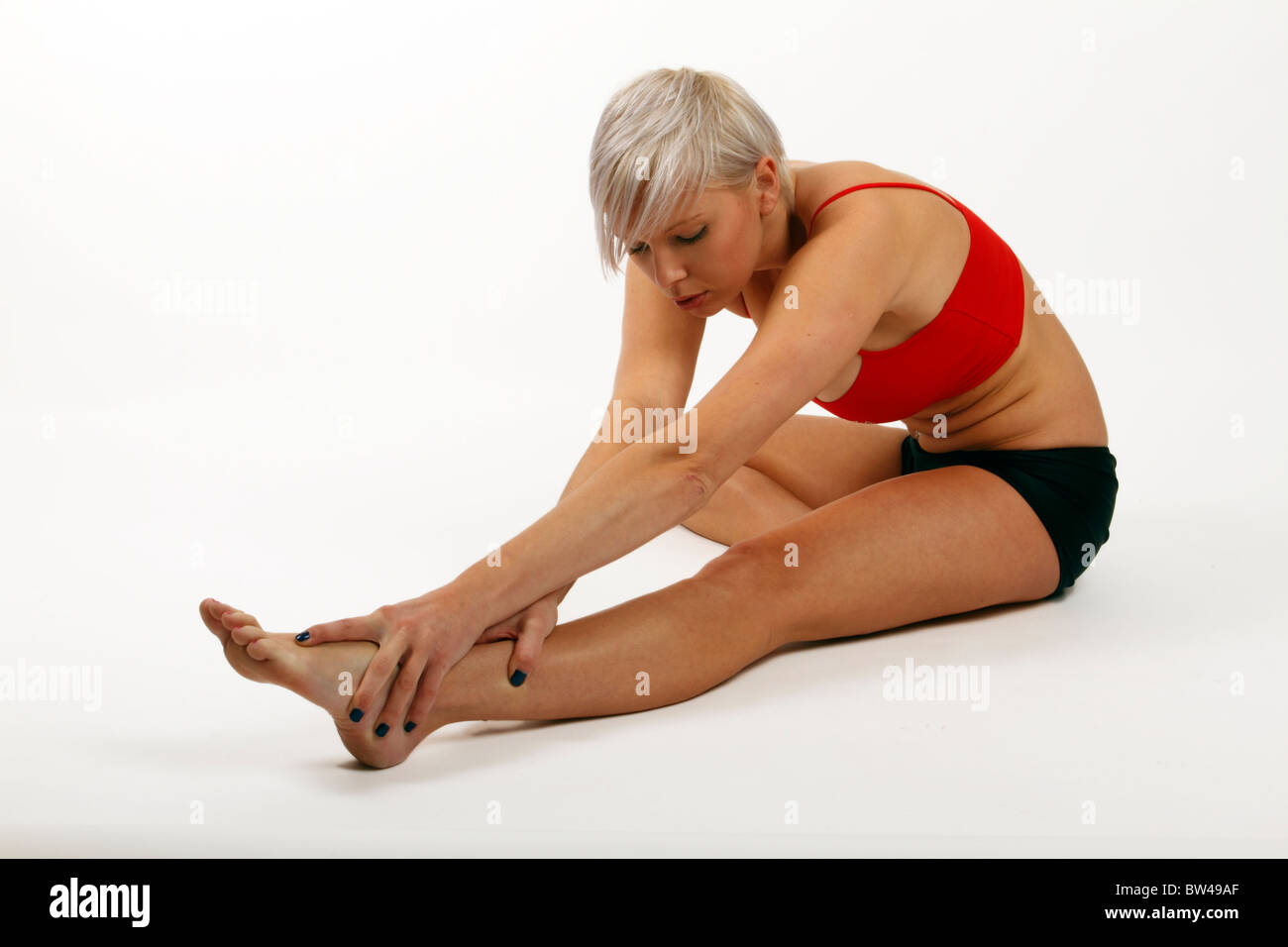 junge trendige Fit Frau streckte ihre Muskeln in den Beinen Stockfoto
