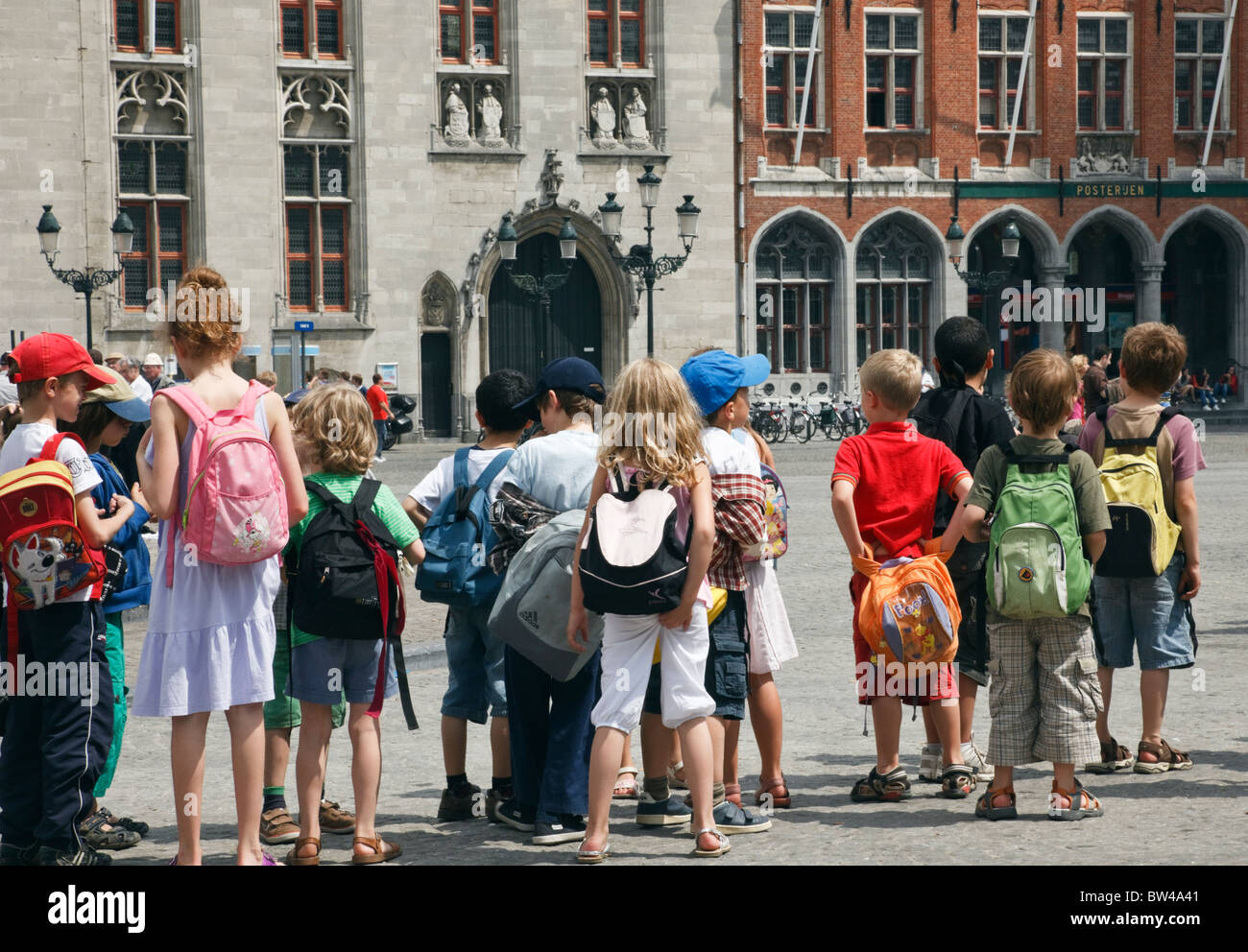 Markt, Brügge, Belgien, Europa. Gruppe von Kindern tragen Rucksäcke auf einer Klassenfahrt auf dem historischen Stadtplatz Stockfoto