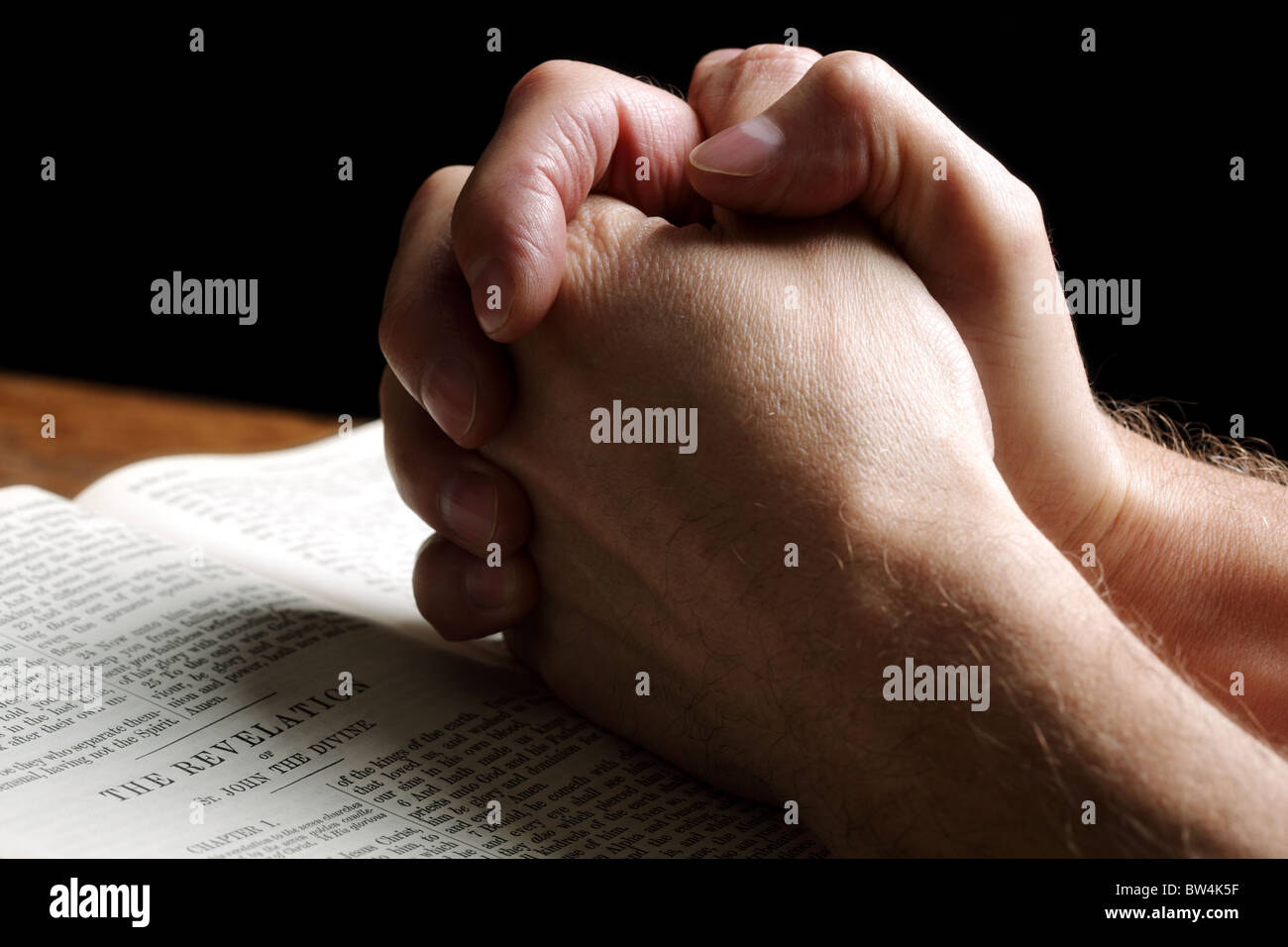 Betende Hände auf eine aufgeschlagene Bibel Stockfoto