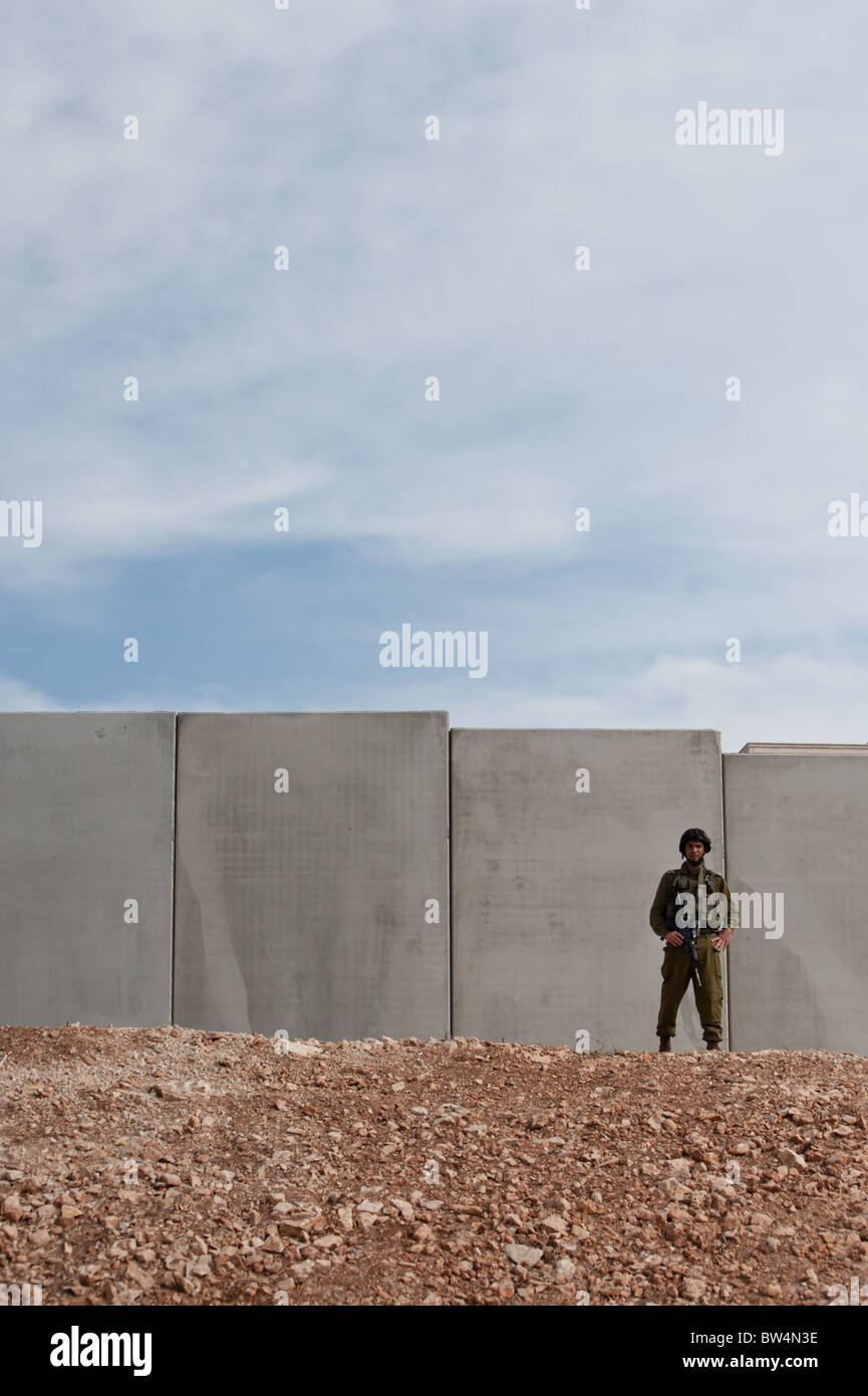 Ein israelischer Soldat stehen vor der israelischen Sperranlage droht der Westbank-Stadt von Al-Walaje einzukreisen. Stockfoto