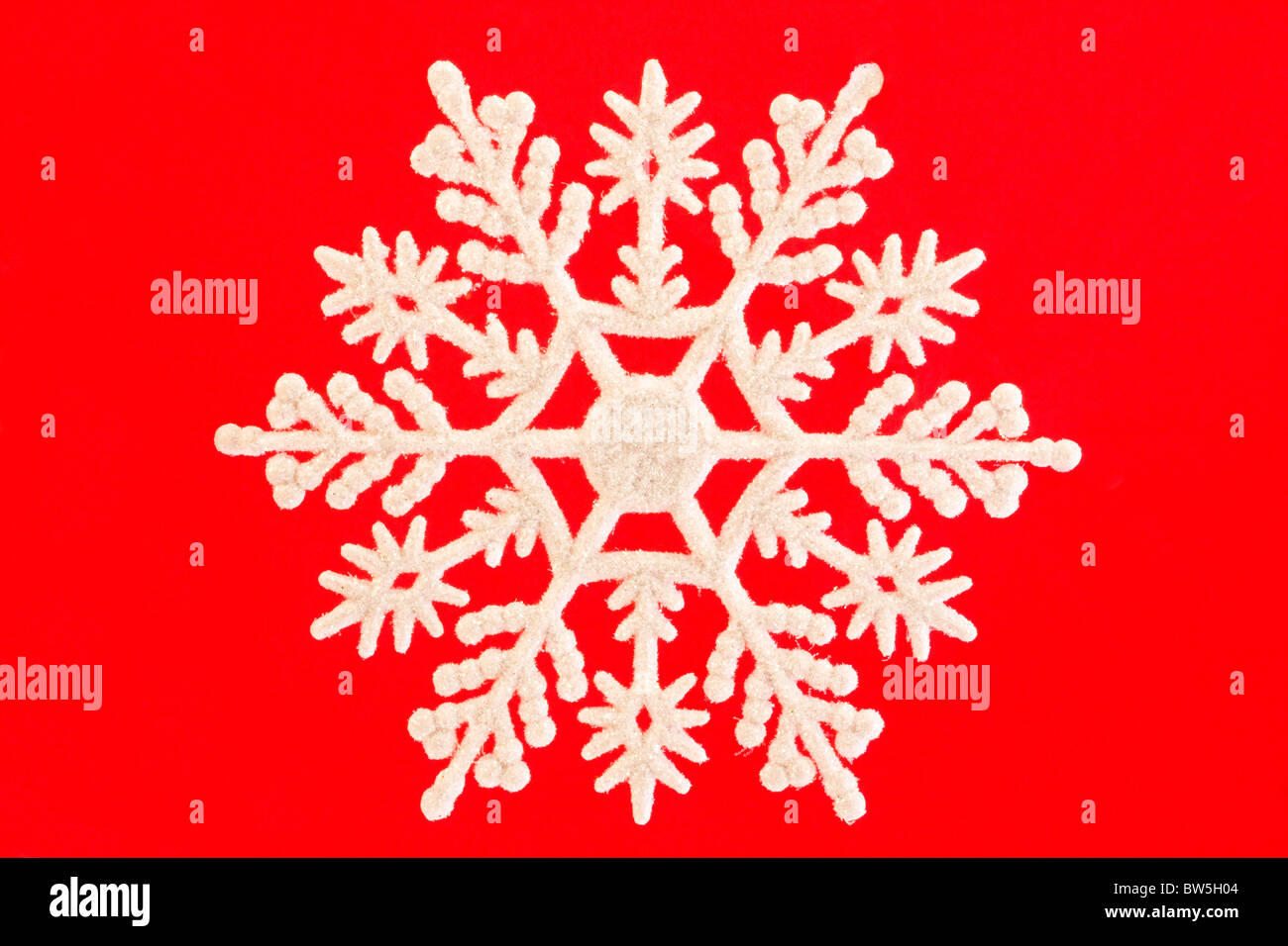 einzelne Weiße Schneeflocken über rot isoliert Stockfoto