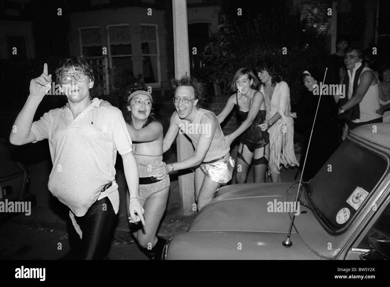 Mittelklasse schicke Kostümparty Weihnachtsfeier, die den Conga Line Tanz auf der Straße macht. Wimbledon SW19 London England UK 1980s 1983 HOMER SYKES Stockfoto