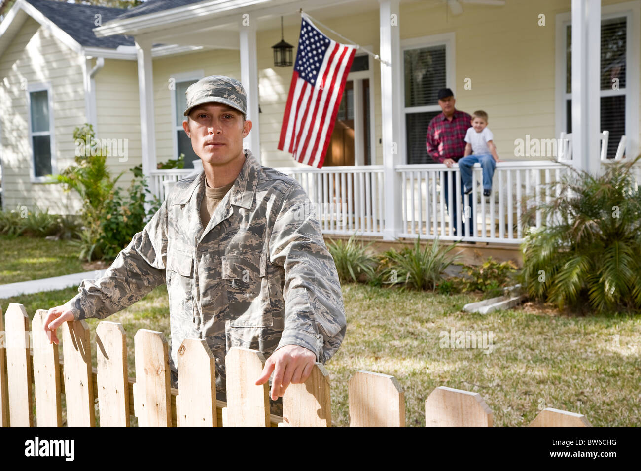 Mann des Militärs, Familie im Hintergrund durch amerikanische Flagge Stockfoto