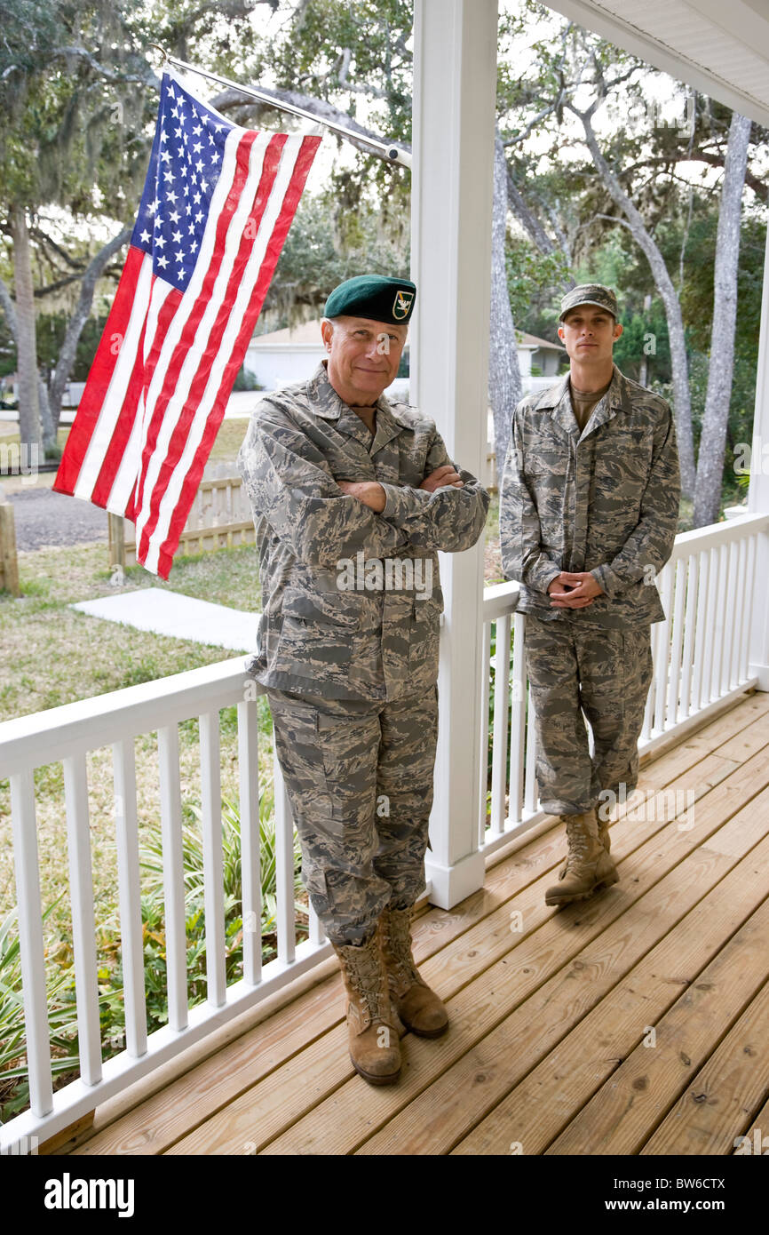 Vater und Sohn in militärischen Uniformen durch amerikanische Flagge Stockfoto