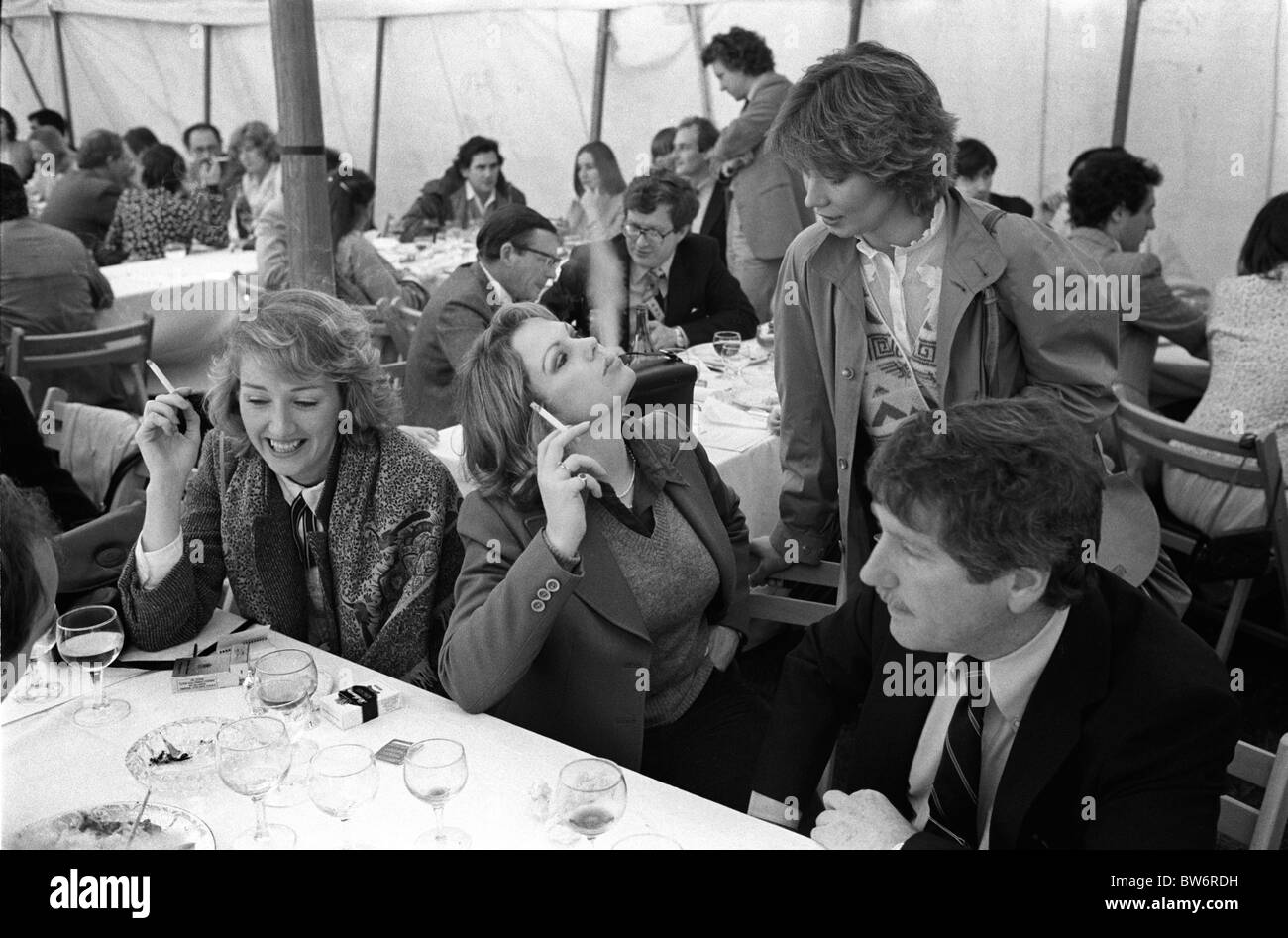 Zigaretten rauchen 1980er Jahre UK zwei Frauen nach dem Mittagessen im Cowdray Park Polo Club. West Sussex. Wohlhabender Lebensstil. Zigarettenrauch von ihrem Freund wegblasen. 80er Jahre Großbritannien 1981 HOMER SYKES Stockfoto