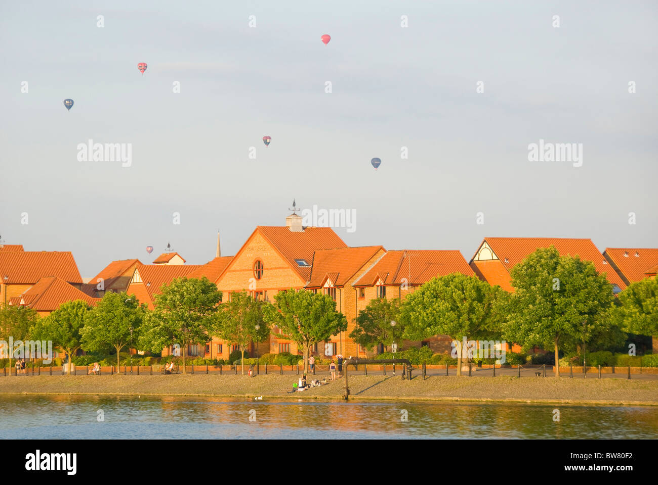 Häuser und Bäume entlang schwimmenden Hafen, Heißluftballons, Bristol, UK Stockfoto