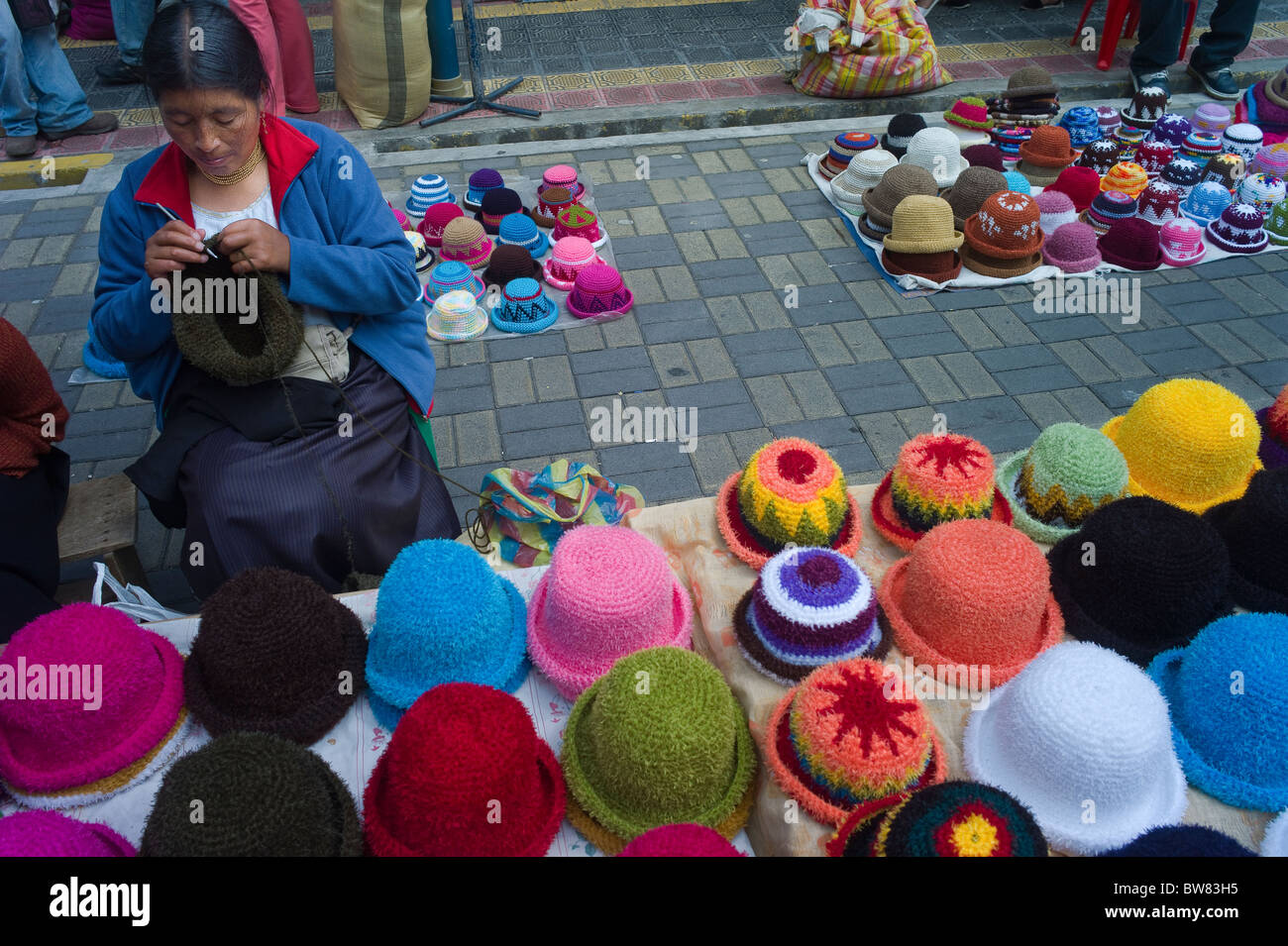 Frau stricken und Hüte auf Bürgersteig, Otavalo, Imbabura, Ecuador zu verkaufen Stockfoto