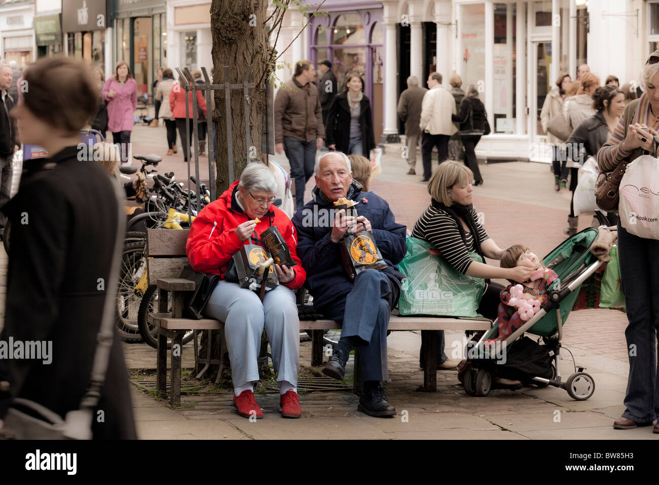 zwei ältere Menschen Essen zum Mitnehmen cornish Pasties auf einer Stadt-High-Street-Bank Stockfoto