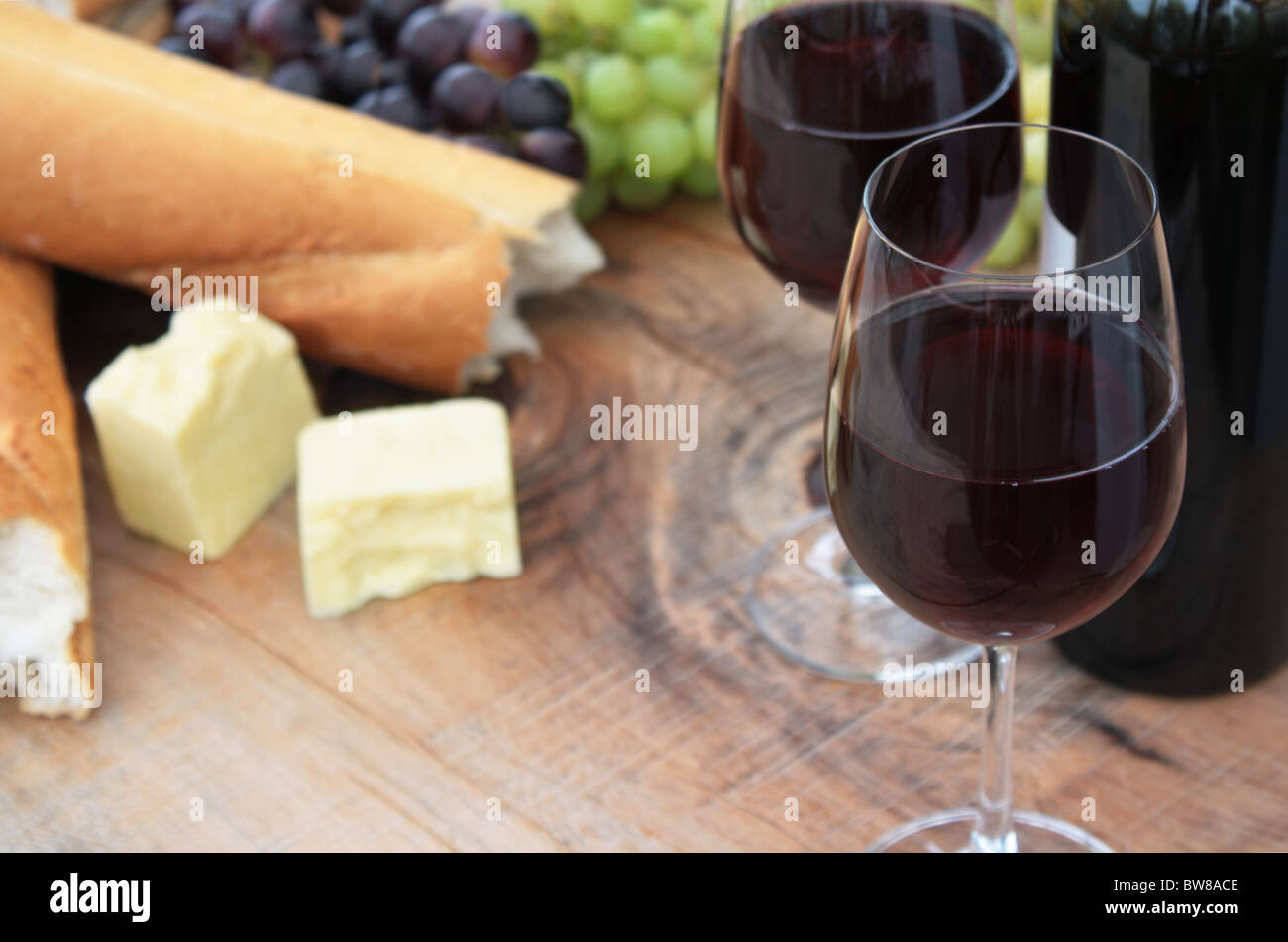 Wein, Brot, Käse, Trauben auf hölzernen Gartentisch Stockfoto