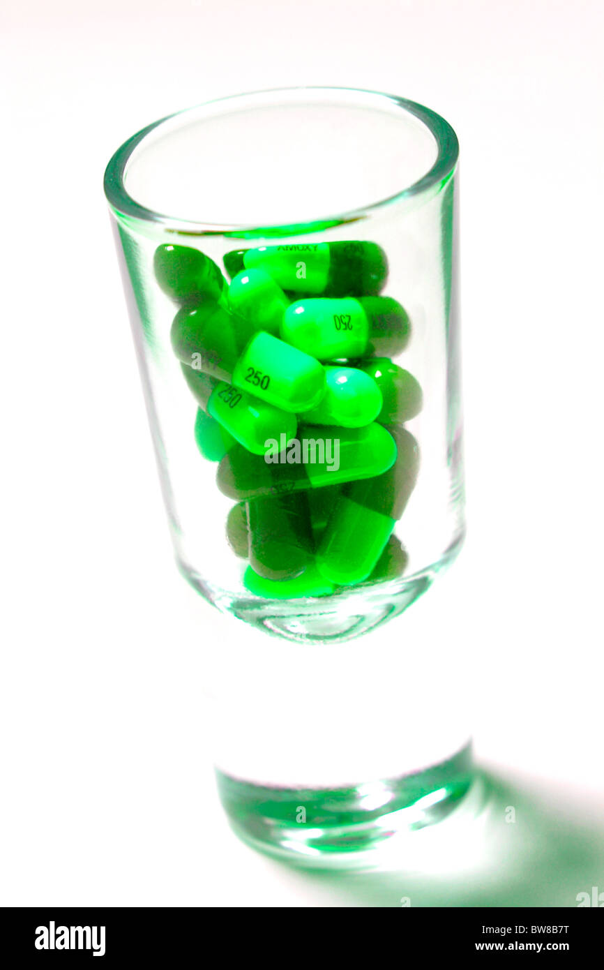 Grüne Pillen in Schnapsglas Stockfoto