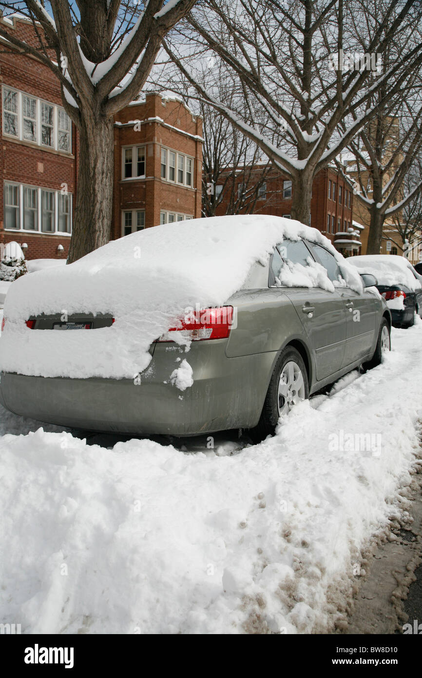 Schnee umgibt und erstreckt sich in einer Seitenstraße Gepflügtes Stadt im Winter geparkten Autos Stockfoto