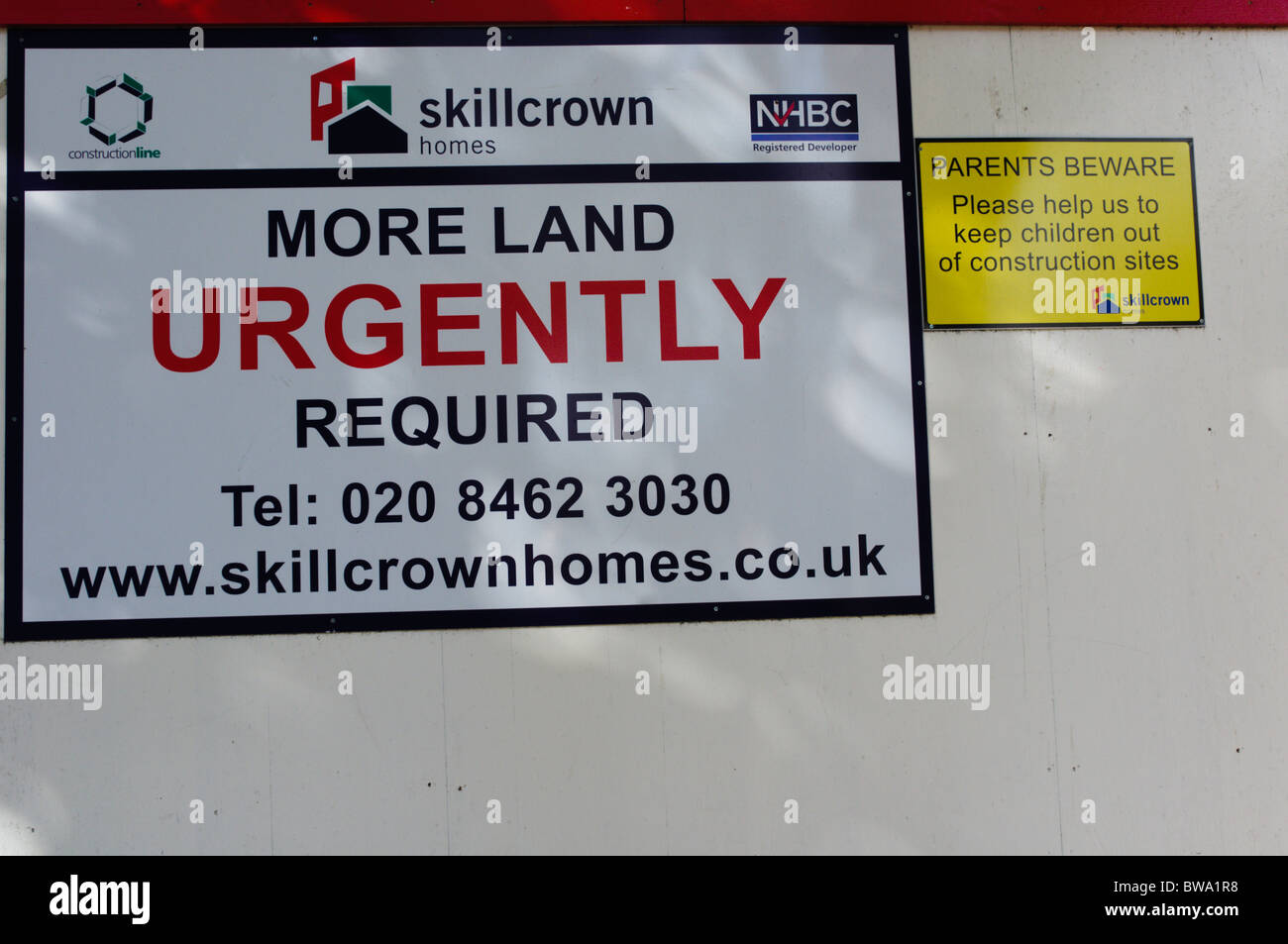 Melden Sie sagen "Mehr Land dringend erforderlich" auf einer Website Horten rund um ein Haus mit dem Namen und Logo von Skillcrown Häusern. Stockfoto