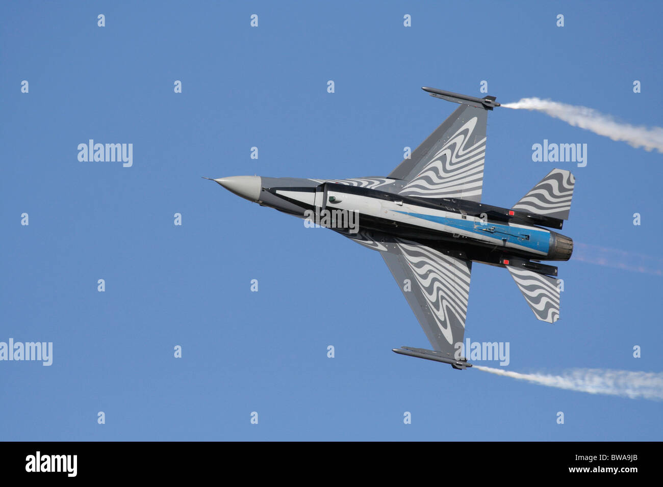 Belgisches F-16 Kampfflugzeug, das während einer Fluganzeige am Himmel fliegt. Unterseite. Nicht zentrierte Komposition mit Kopierbereich. Stockfoto