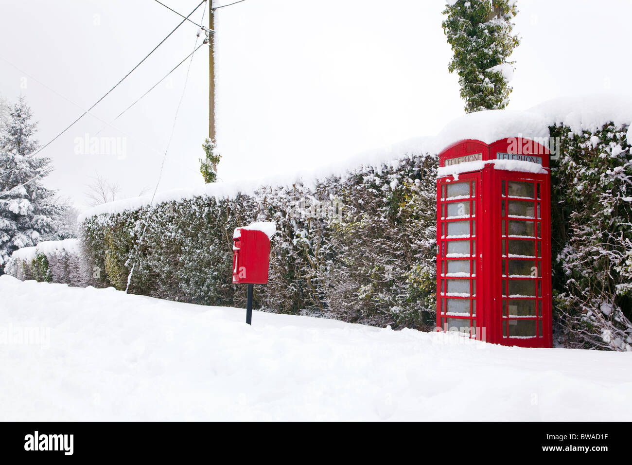 Eine traditionelle rote englische Telefonzelle und Briefkasten nach einem schweren Schneefall. Stockfoto