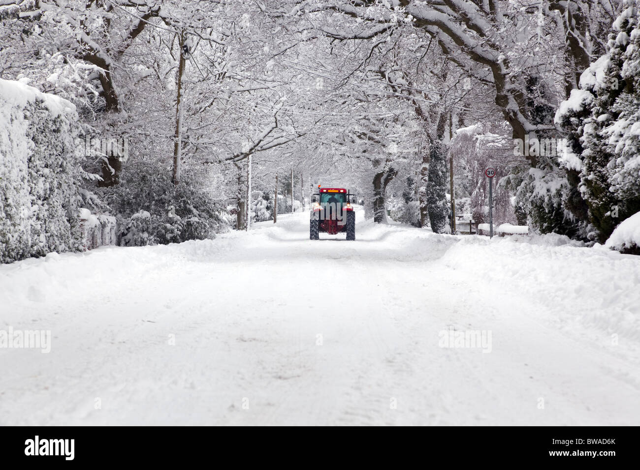 Ein roter Traktor fahren auf Schnee bedeckt UK Straße im Winter Schneefall Winter im Januar 2010 Stockfoto