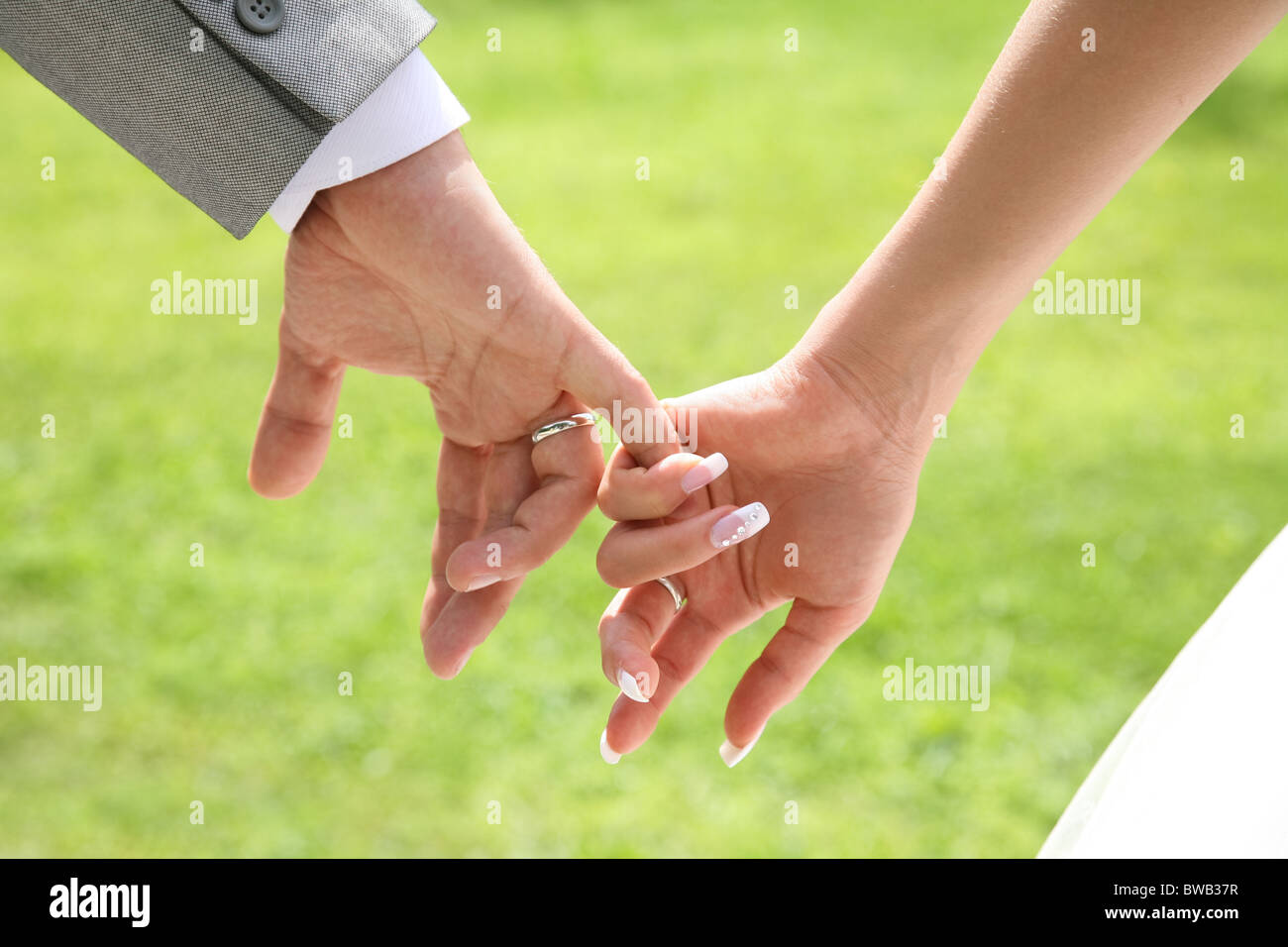 Close-up der Braut Hand hält, die von ihrem Ehemann auf grünem Hintergrund Stockfoto