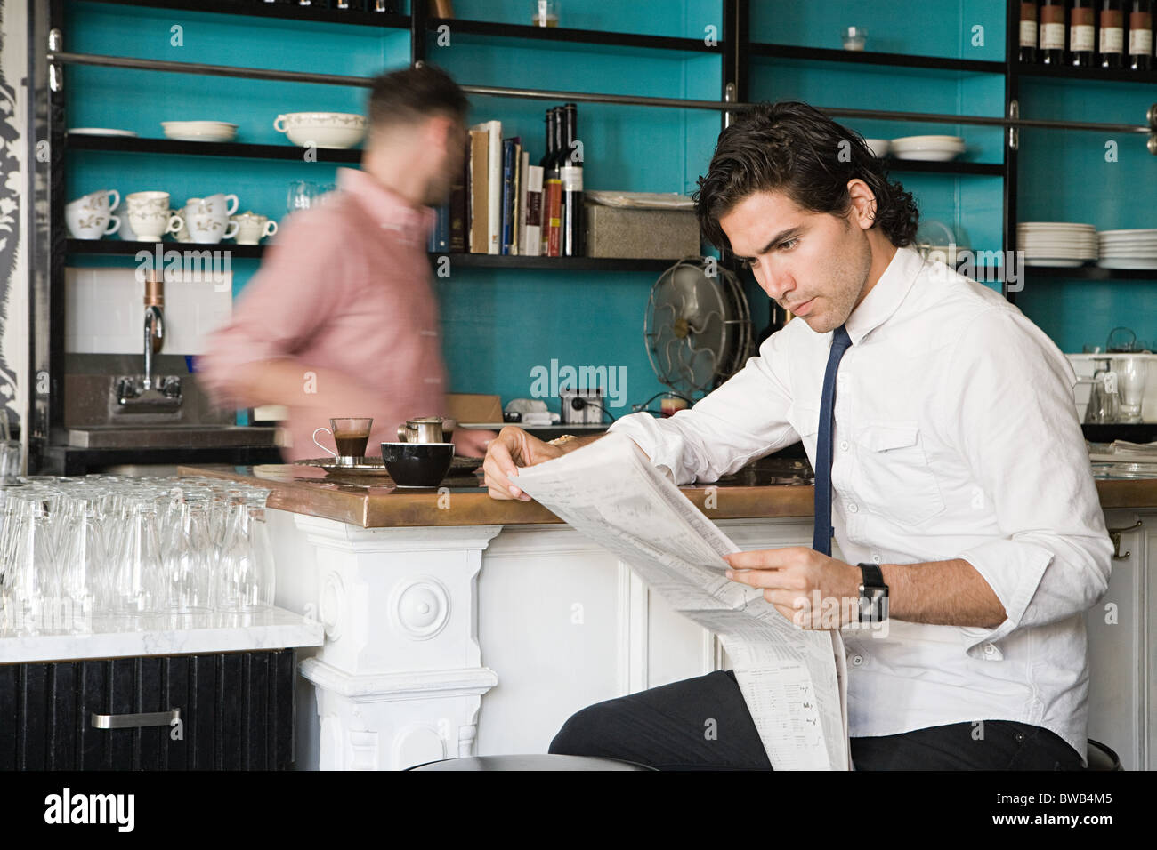Mann mit Zeitung und Kellner im café Stockfoto