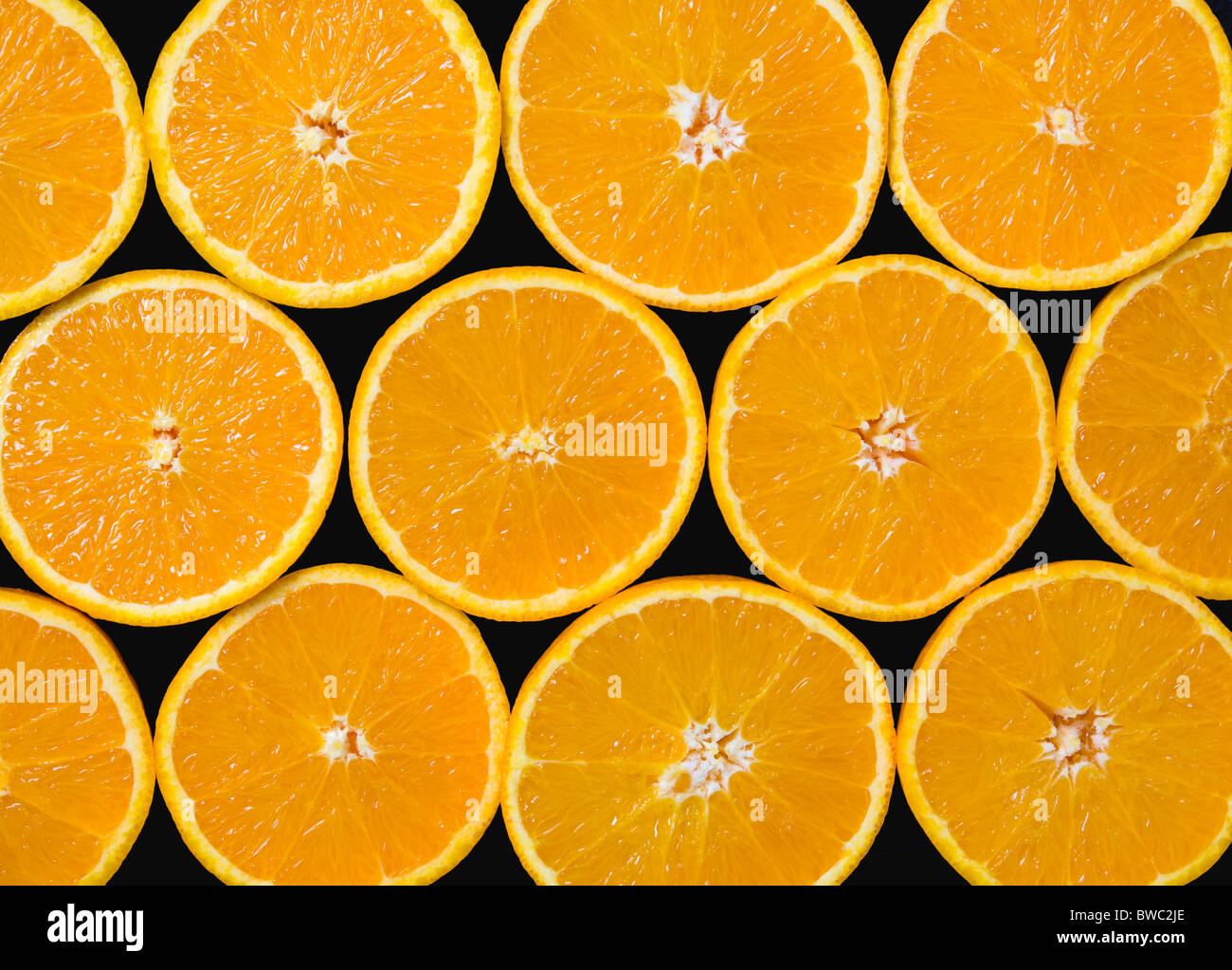 Lebensmittel, Obst, Orangen, Overhead Blick auf Gruppe von Orangen schneiden in der Hälfte zeigt Kern und Segmente vor einem schwarzen Hintergrund. Stockfoto