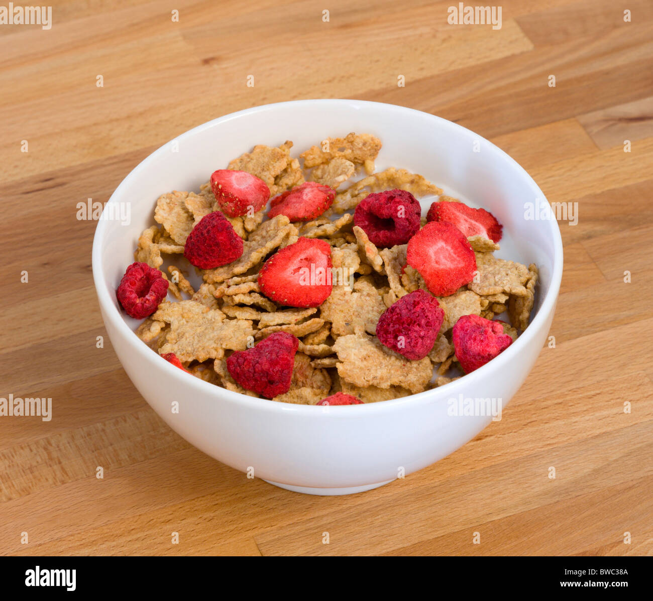 Essen, Speisen, Müsli, weiße Frühstück Schüssel mit Kleie-Flocken-Müsli mit Einfrieren getrocknete Früchte der Erdbeeren und Himbeeren in Milch Stockfoto