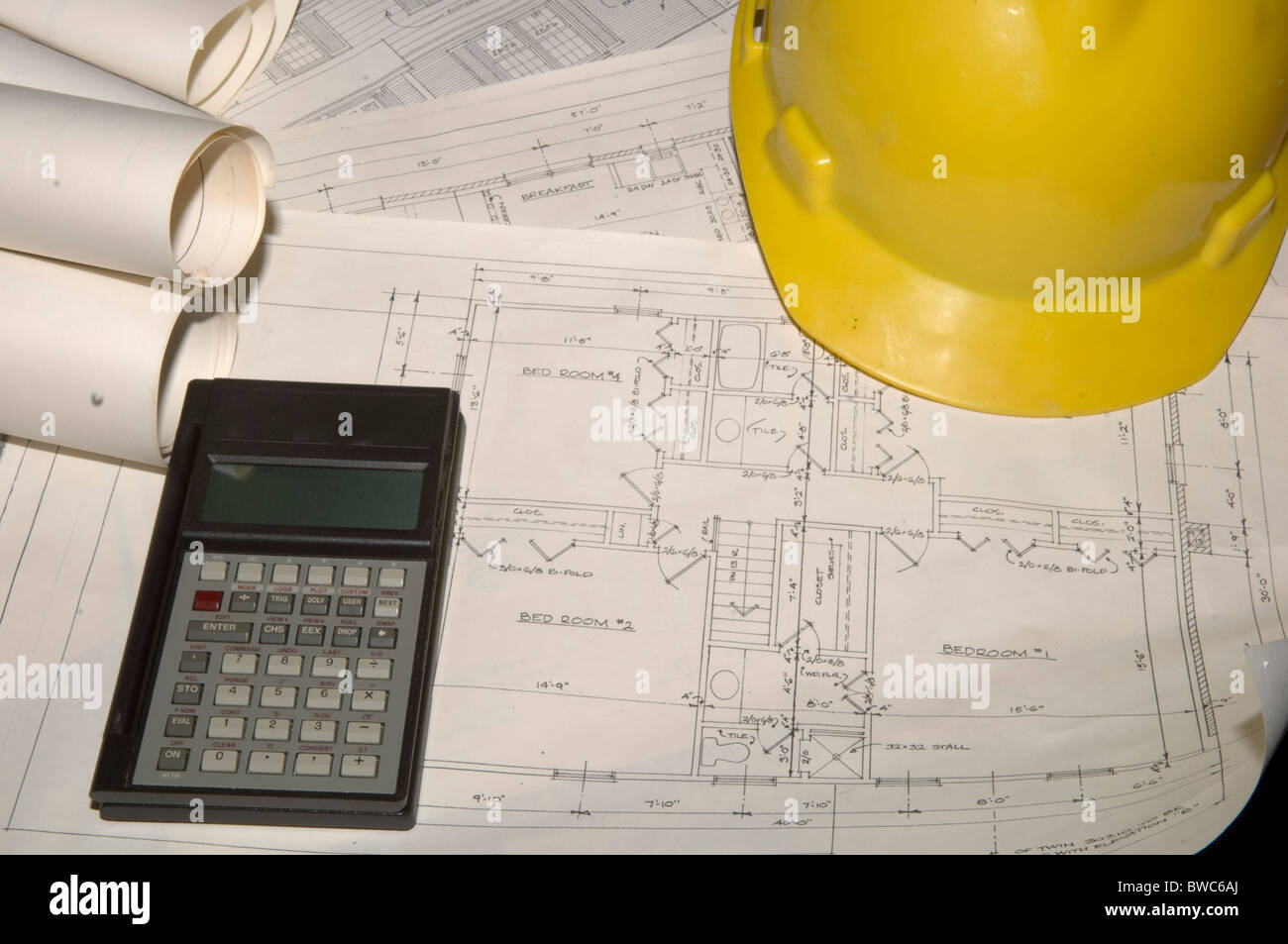 Blaupausen mit Schutzhelm und Taschenrechner. Stockfoto