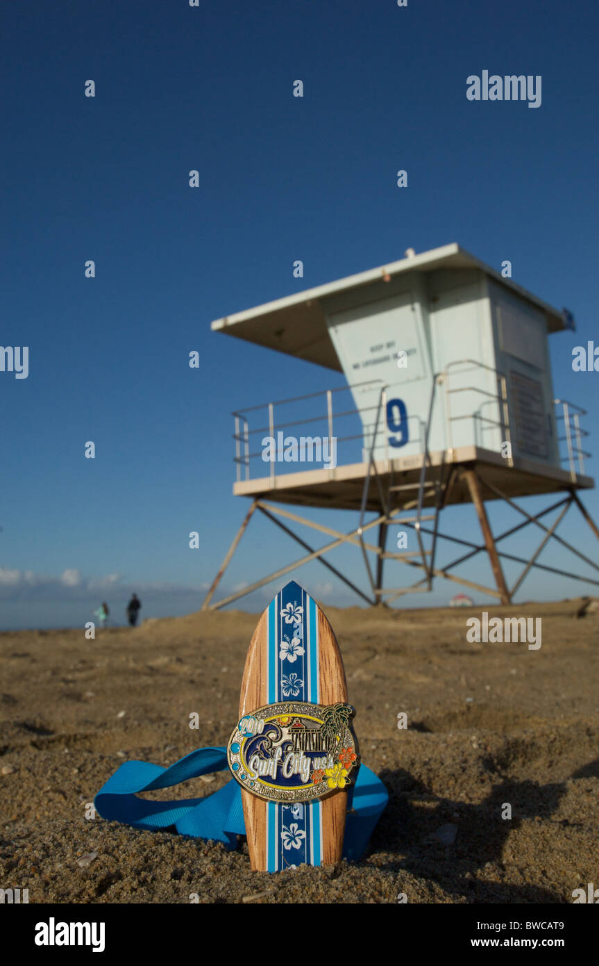 Eine Teilnahme-Medaille aus Huntington Beach Surf City 5k sitzt im Sand. Stockfoto
