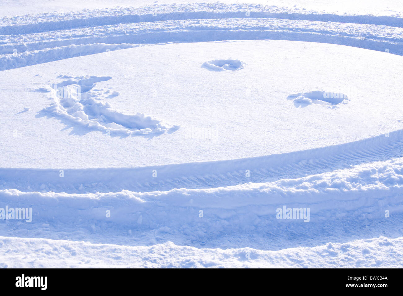 Bild des rundes Gesicht mit Augen und Lächeln gezeichnet auf Schnee Stockfoto