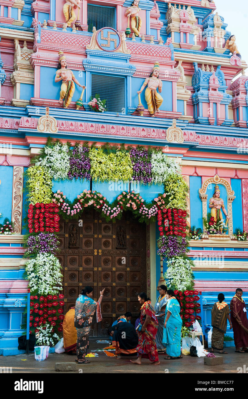 Indische Frauen dekorieren Sathya Sai Babas Gopuram Tempel Eingang mit Blumen und rangoli in der indischen Stadt Puttaparthi. Andhra Pradesh, Indien Stockfoto