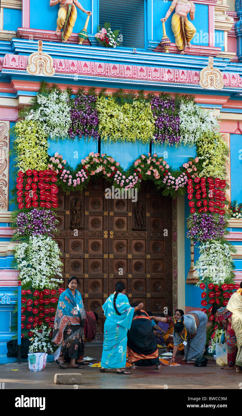 Indische Frauen dekorieren Sathya Sai Babas Gopuram Tempel Eingang mit Blumen und rangoli in der indischen Stadt Puttaparthi. Andhra Pradesh, Indien Stockfoto