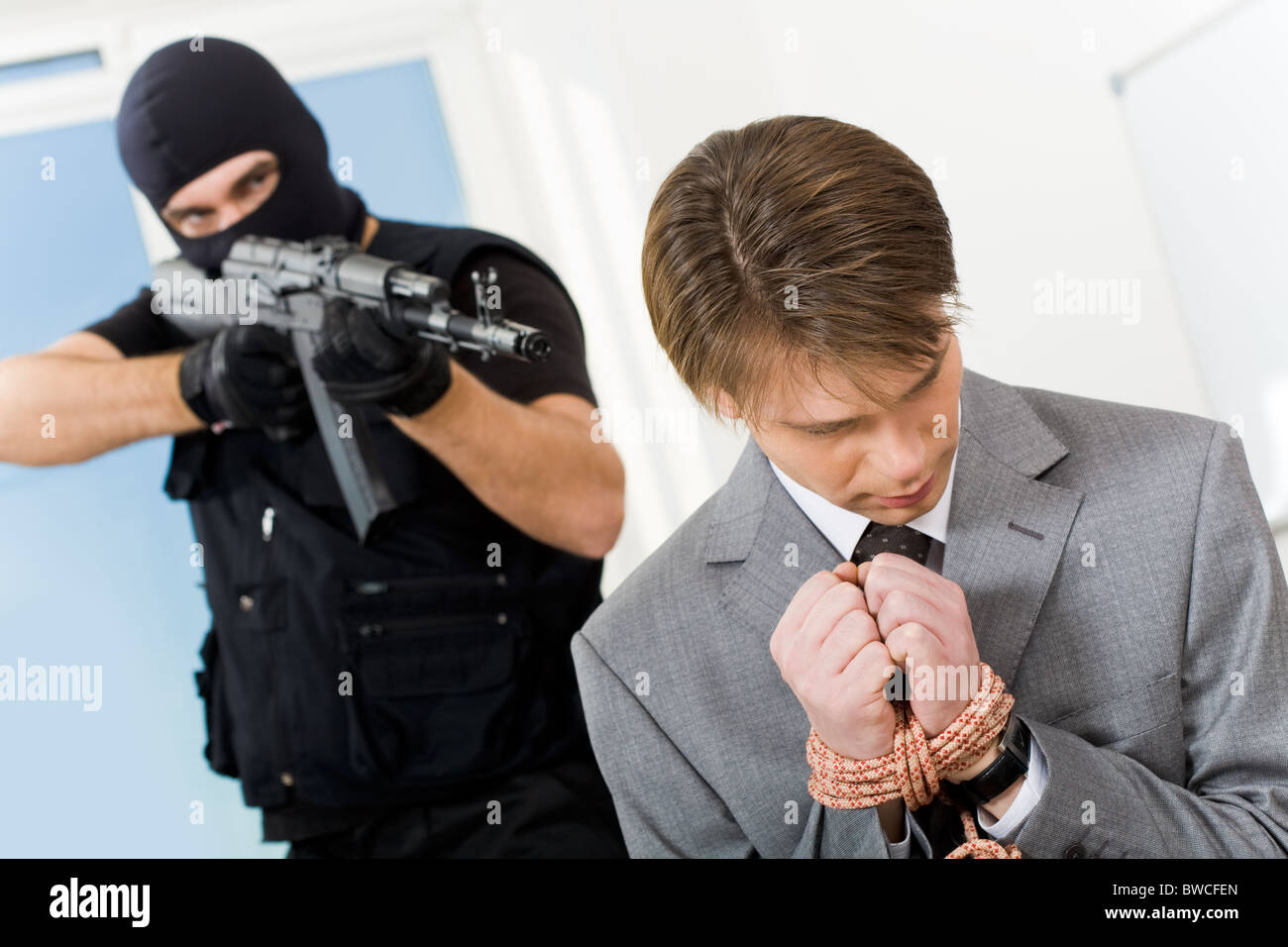 Porträt von verwirrt Geschäftsmann mit gefesselten Händen gejagt von Gangster zeigenden Waffe auf ihn Stockfoto