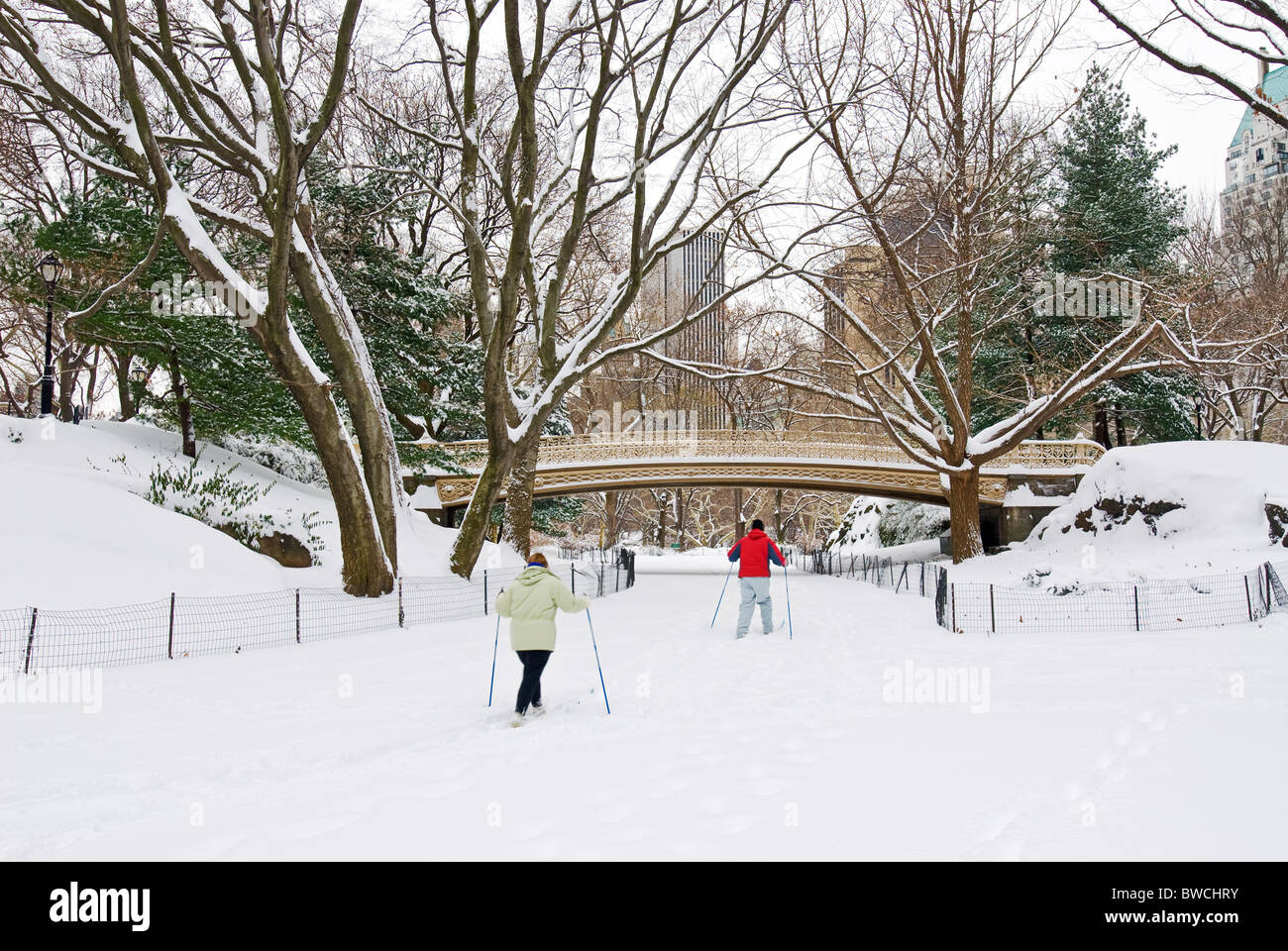 Paar Langlaufski durch heitere Brücke im Winter Schnee, Central Park, New York City. Stockfoto