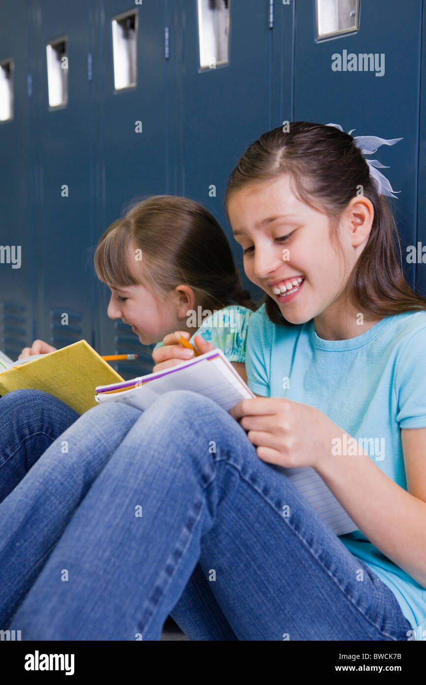 USA, Illinois, Metamora, zwei Mädchen (8-9) sitzen an Schließfächern im Flur der Schule und Hausaufgaben Stockfoto