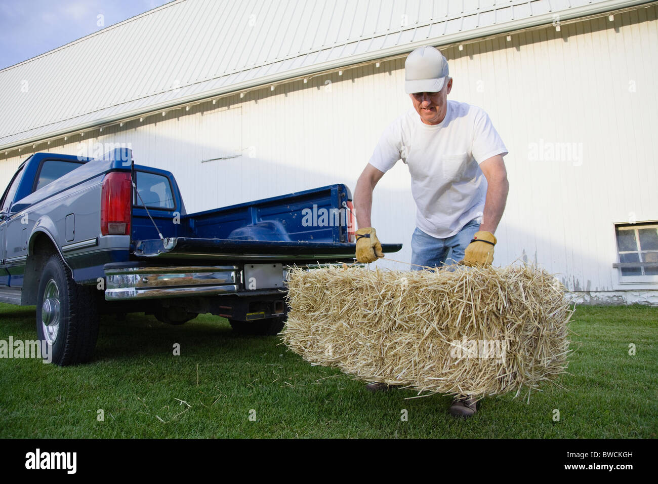USA, Illinois, Metamora, Landwirt anhebende Heuballen auf Bauernhof Stockfoto