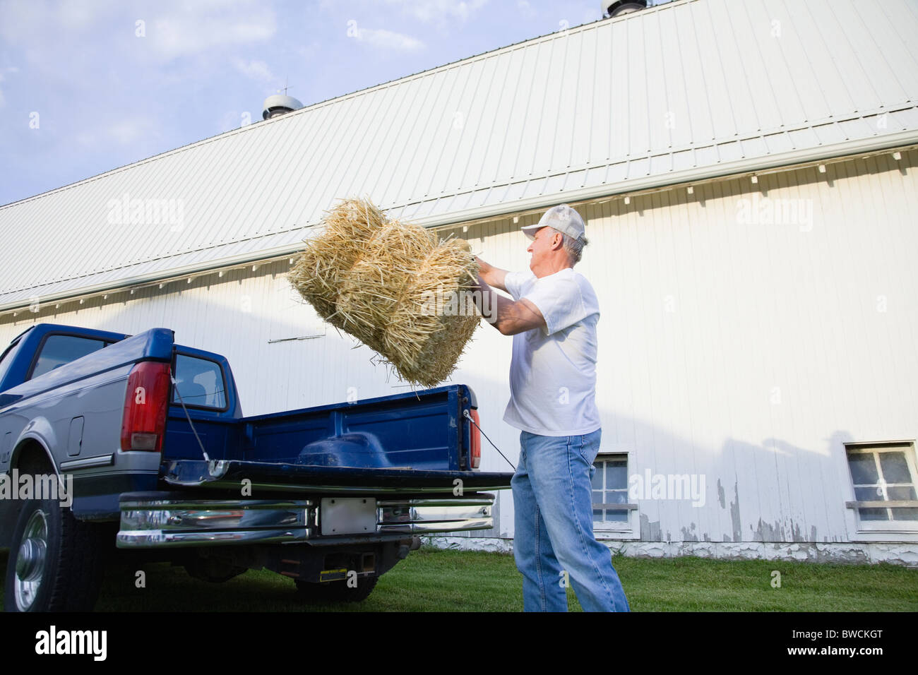 USA, Illinois, Metamora, Landwirt anhebende Heuballen auf Bauernhof Stockfoto