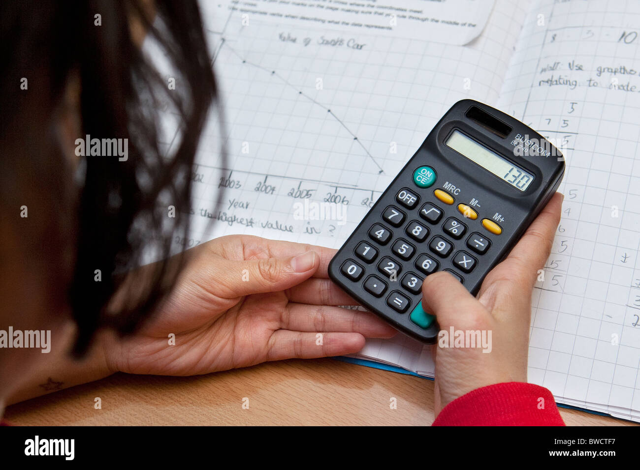 Kind mit einem Taschenrechner in Mathematik Schulstunde Stockfoto