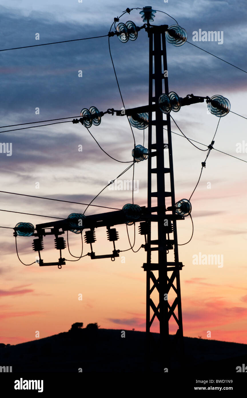 Kleine Strommast mit Stromleitungen verbinden in gebogene Drähte durch Glas Isolatoren, Silhouette gegen den Abend sk Stockfoto