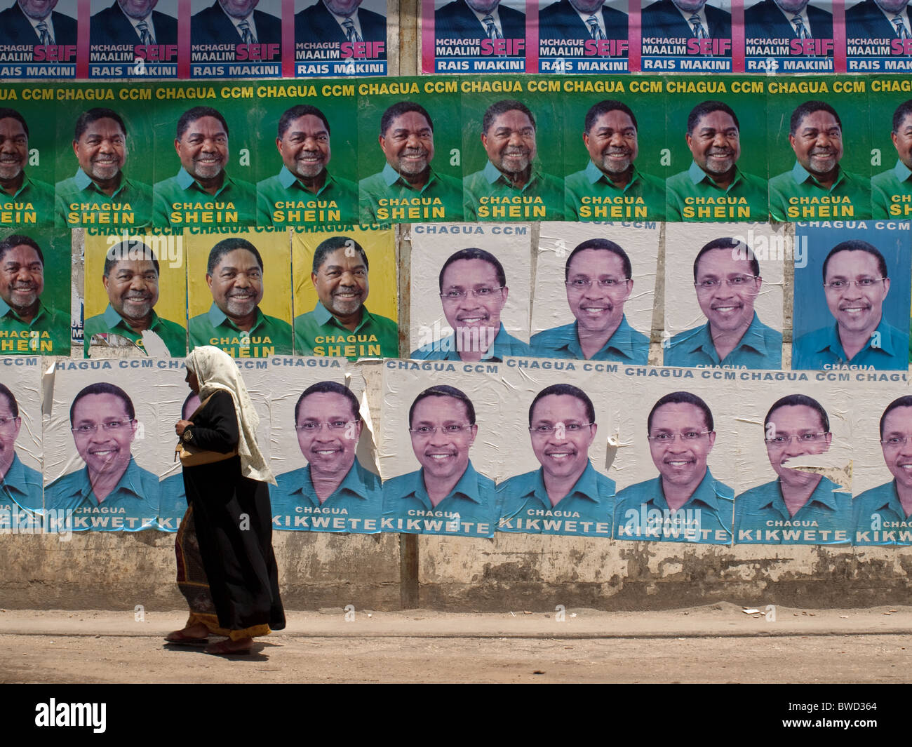 Zanzibar Frau vorbei an bunten Wand des ununterbrochenen Wahlplakate in Stonetown Stockfoto
