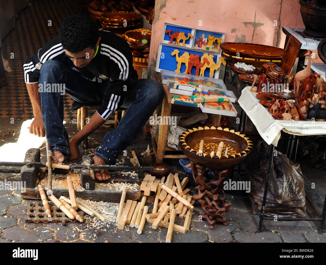 Ein Handwerker schnitzt Artikel aus Holz mit einer Drehbank mit seinen Füßen in einem Souk in Marrakesch. Stockfoto