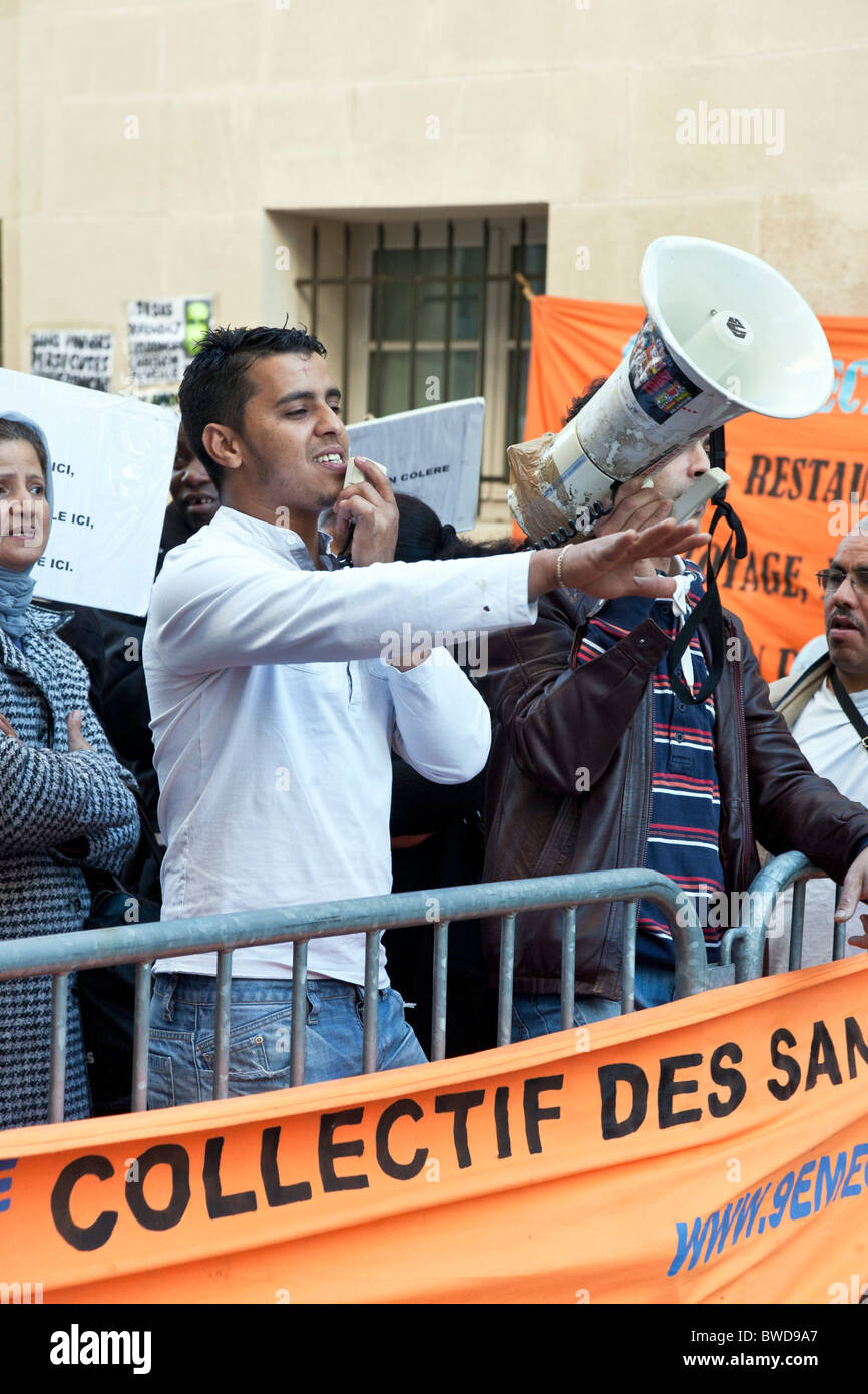 fröhlicher Junge arabische Mensch mit Mikrofon führt Gesang bei Straßendemonstration des französischen Schwarzarbeiter sans papiers Stockfoto
