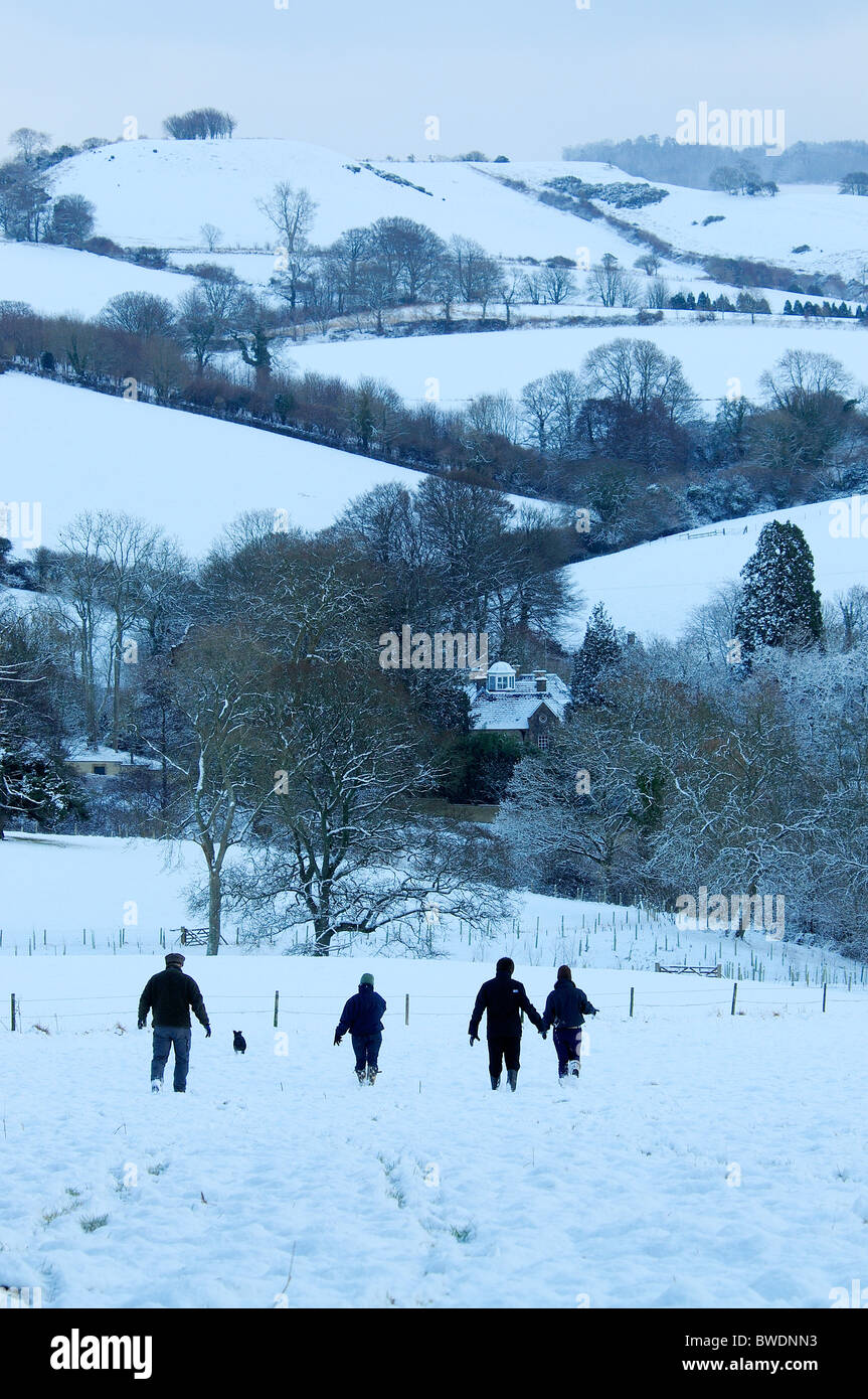 Vier Personen und ein Hund zu Fuß hinunter einen Hügel im Schnee. Dorset, UK-Februar 2009 Stockfoto