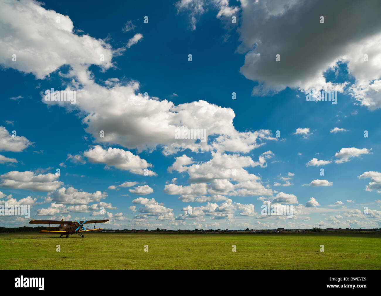 Gelbe Flugzeug auf grüne Flugplatz unter blauem Himmel mit weißen Wolken Stockfoto