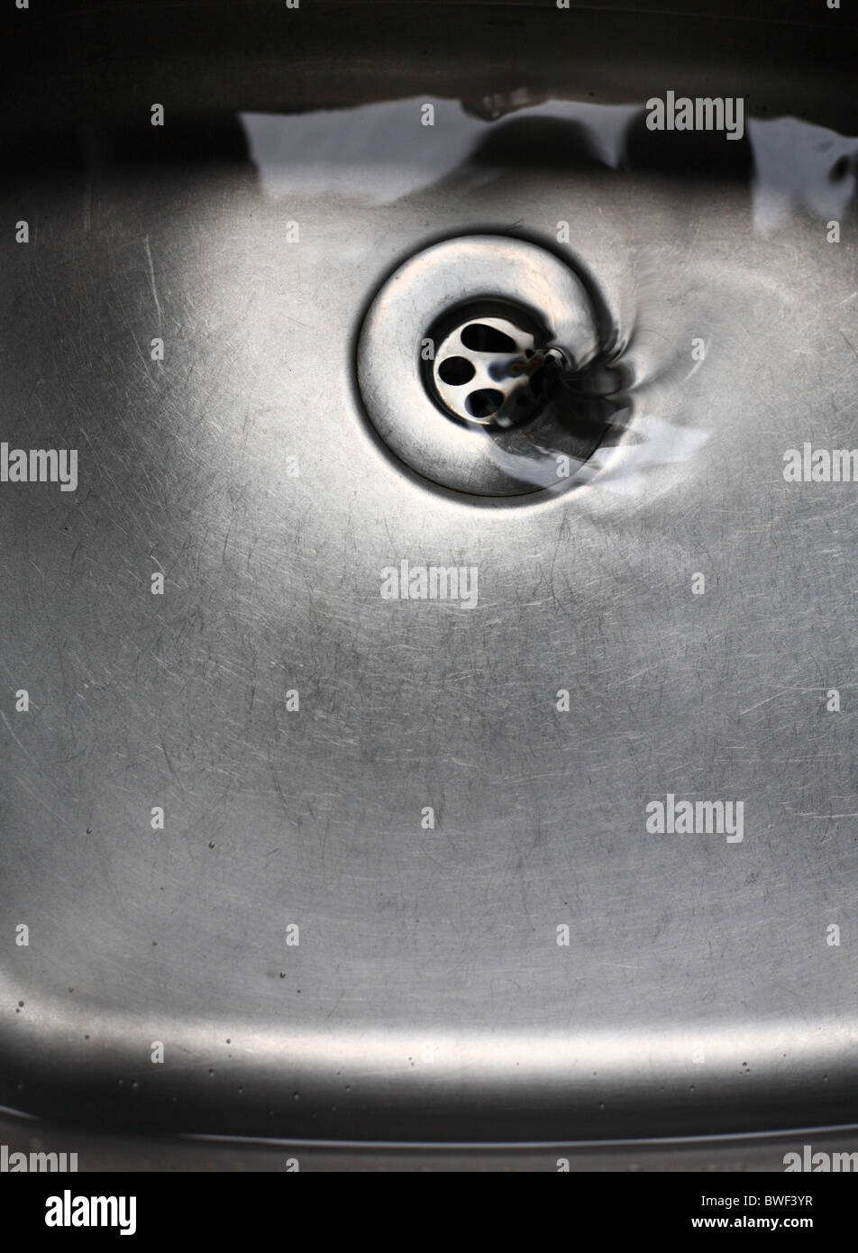 Wasser verschwindet hinunter den Abfluss im Waschbecken. Stockfoto