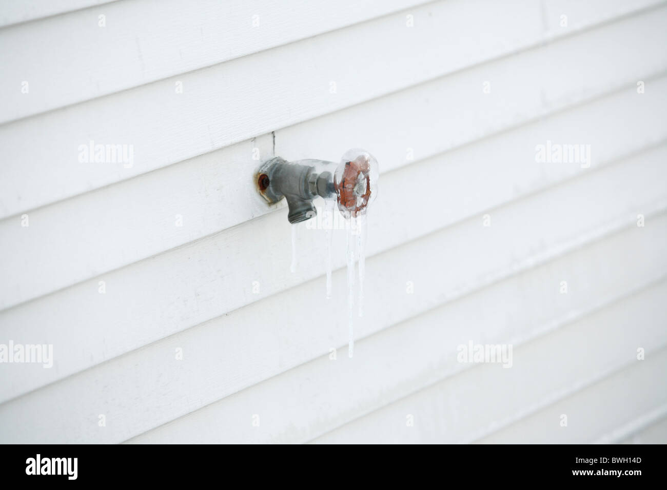 Eis und Eiszapfen an einem Wasserhahn Hahn an der Seite eines Hauses Stockfoto