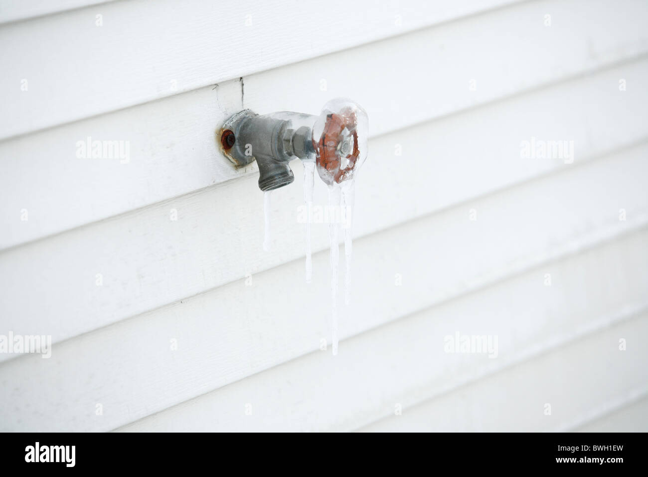 Eis und Eiszapfen an einem Wasserhahn Hahn an der Seite eines Hauses Stockfoto