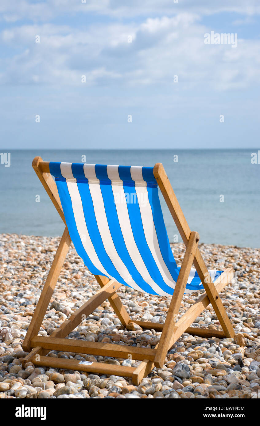 England, West Sussex, Bognor Regis, einzelne blaue und weiße Liegestuhl am Kiesstrand Schindel Blick auf das Meer. Stockfoto