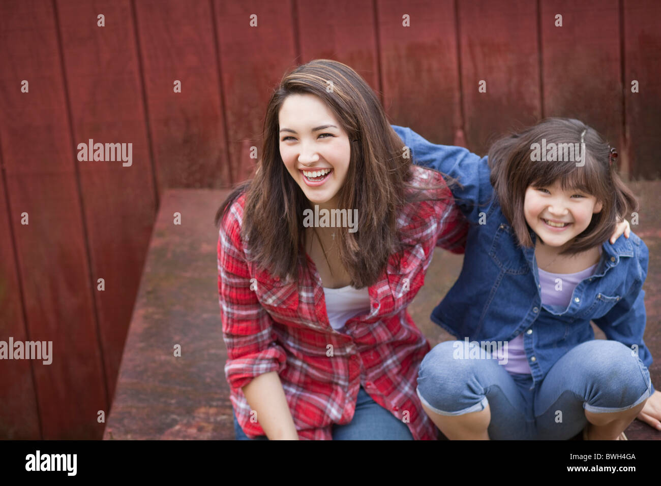 Mädchen mit Schwester sitzen Scheune Stockfoto