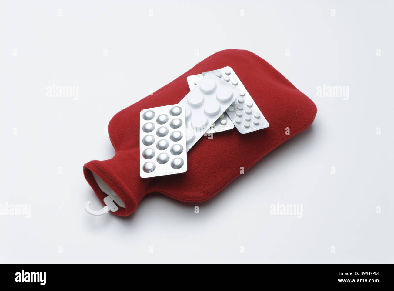 Wärmflasche mit rotem Einband und Tabletten in Blisterpackungen Stockfoto